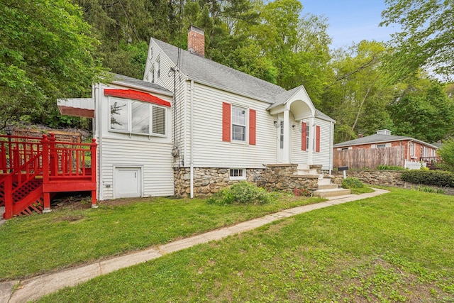 bungalow-style home featuring a chimney, a front yard, a shingled roof, and a wooden deck