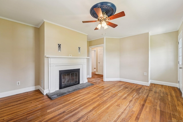 unfurnished living room with a ceiling fan, a glass covered fireplace, wood finished floors, baseboards, and crown molding