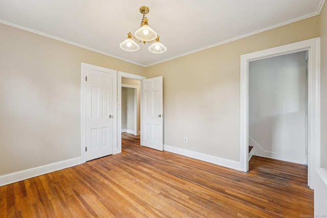 unfurnished bedroom featuring light wood-type flooring, baseboards, ornamental molding, and a chandelier