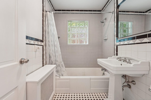 bathroom with tile walls, shower / tub combo, and plenty of natural light