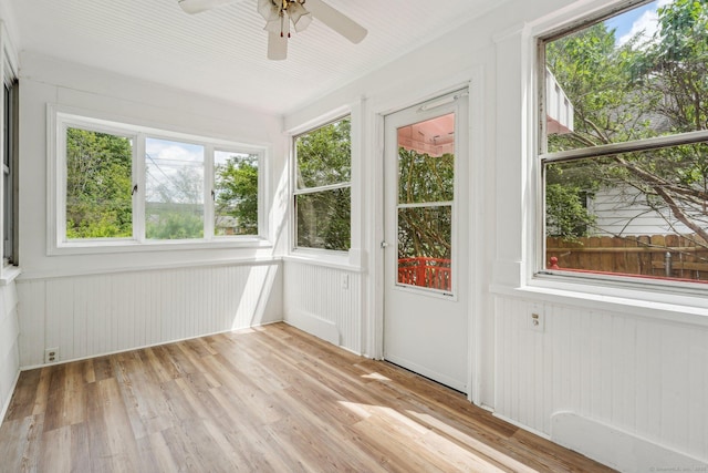 unfurnished sunroom with plenty of natural light, wood finished floors, and wooden walls