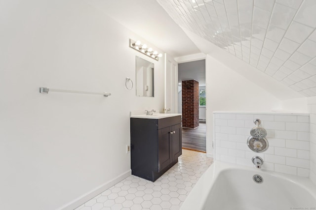 bathroom featuring tile patterned flooring, a garden tub, vanity, baseboards, and lofted ceiling