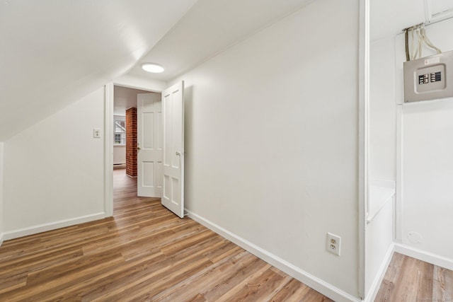 additional living space featuring light wood-style flooring, baseboards, and vaulted ceiling