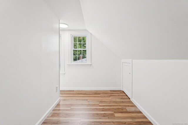 bonus room with light wood finished floors, lofted ceiling, and baseboards