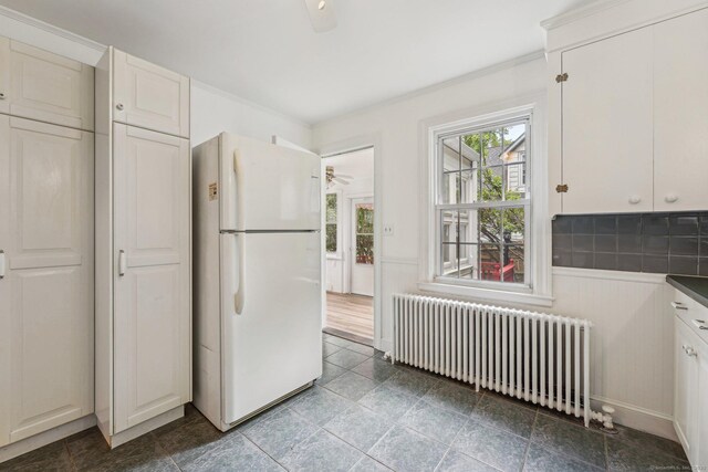 kitchen featuring freestanding refrigerator, radiator heating unit, a ceiling fan, dark countertops, and ornamental molding