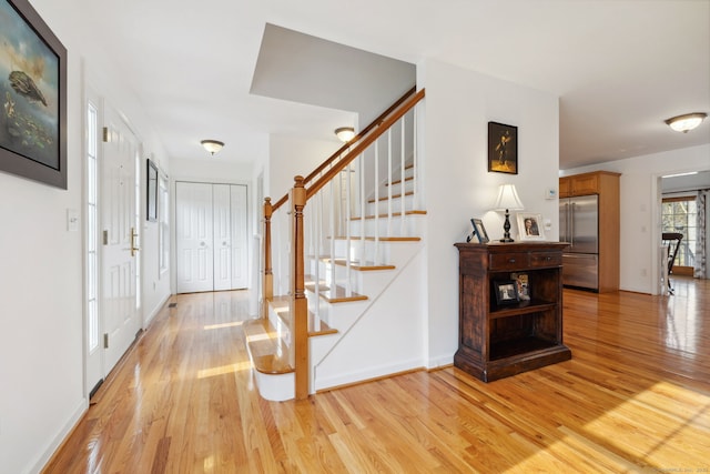foyer featuring stairs, baseboards, and light wood-type flooring
