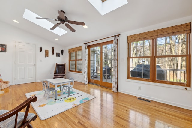 living area with light wood finished floors, ceiling fan, lofted ceiling with skylight, visible vents, and baseboards
