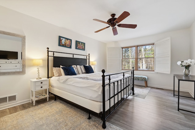 bedroom featuring wood finished floors, visible vents, a ceiling fan, and baseboards