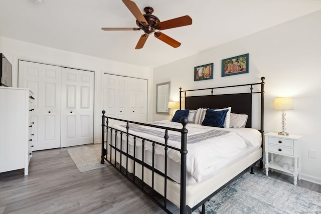 bedroom with baseboards, wood finished floors, ceiling fan, and multiple closets