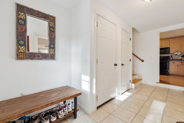 hallway with light tile patterned floors, stairway, and baseboards