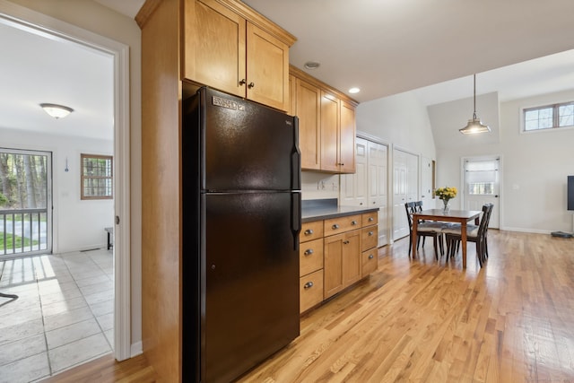 kitchen featuring dark countertops, light wood-style floors, freestanding refrigerator, baseboards, and decorative light fixtures