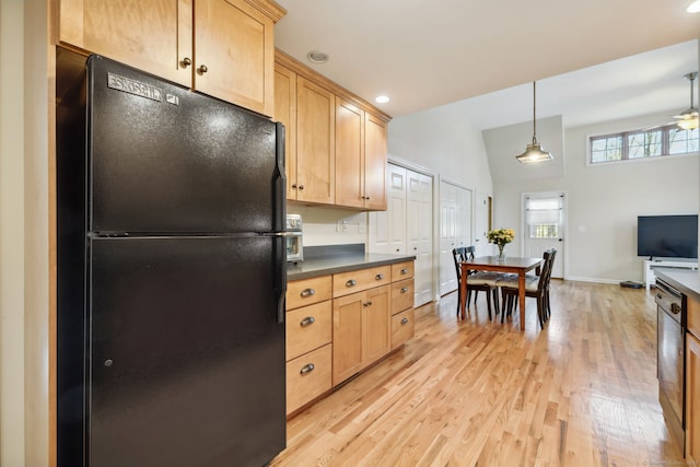 kitchen featuring dark countertops, freestanding refrigerator, and light brown cabinets