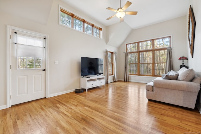 living room with a ceiling fan, baseboards, light wood-style floors, and a healthy amount of sunlight