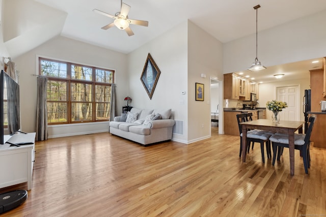 living room with visible vents, ceiling fan, baseboards, light wood-type flooring, and high vaulted ceiling