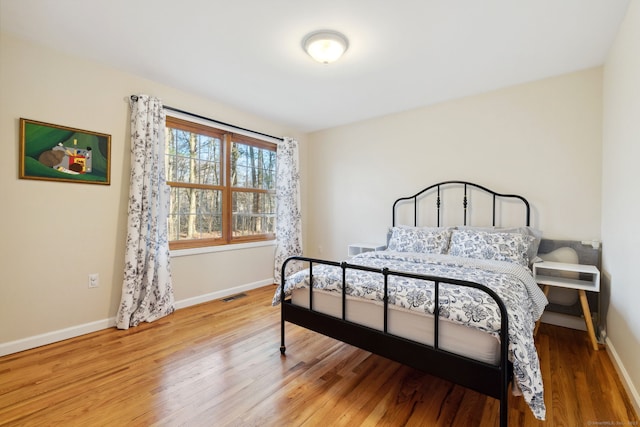 bedroom with visible vents, light wood-style flooring, and baseboards