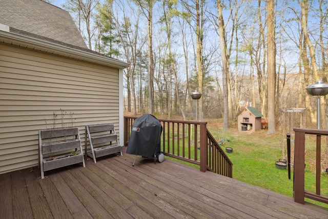 deck featuring an outdoor structure, a lawn, and a grill