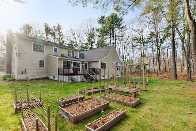rear view of property with a lawn, a wooden deck, and a garden