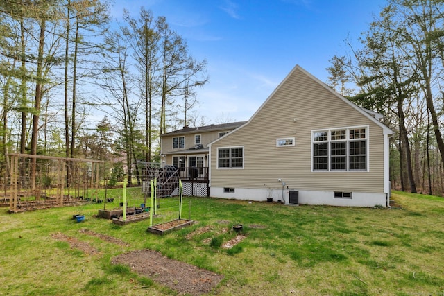 rear view of house with a yard, a vegetable garden, and a wooden deck