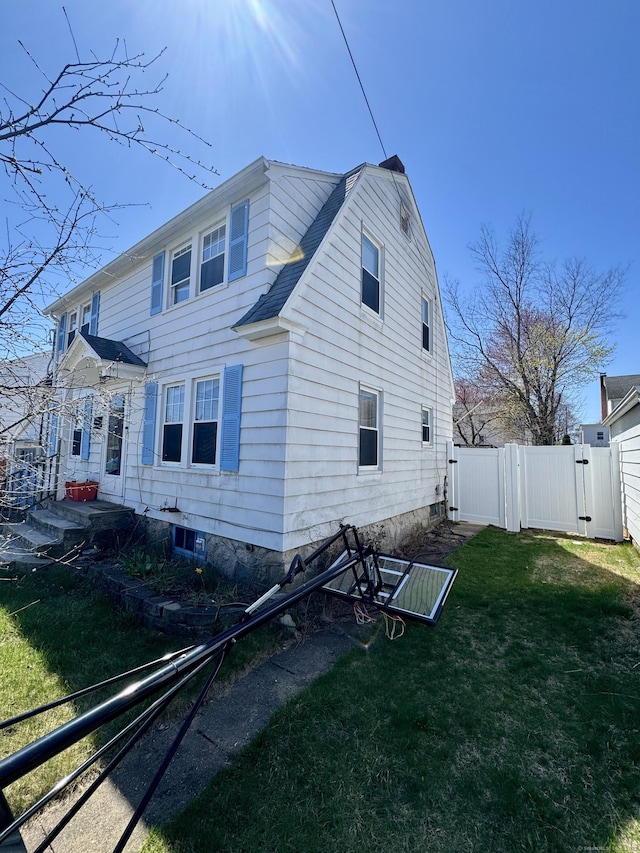 view of property exterior featuring fence, a lawn, a gate, and roof with shingles