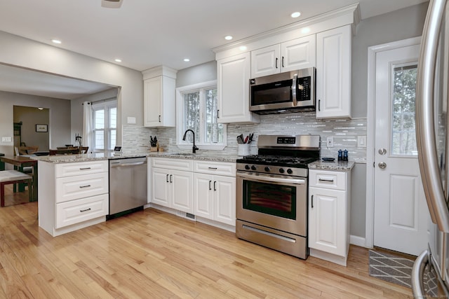 245 Paradise Ave, Hamden, CT 06514 - kitchen featuring a sink, light wood-style floors, stainless steel appliances, a peninsula, and backsplash