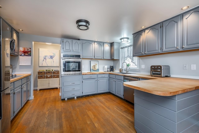 43 Greene Ave, North Canaan, CT 06018 - kitchen with stainless steel appliances, a sink, a peninsula, wood counters, and gray cabinetry