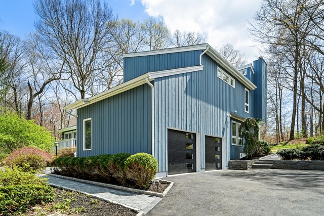 view of side of property with an attached garage, driveway, and a chimney