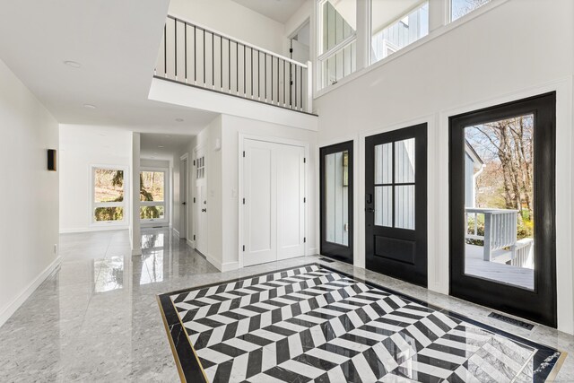 foyer featuring a high ceiling, baseboards, visible vents, and a wealth of natural light