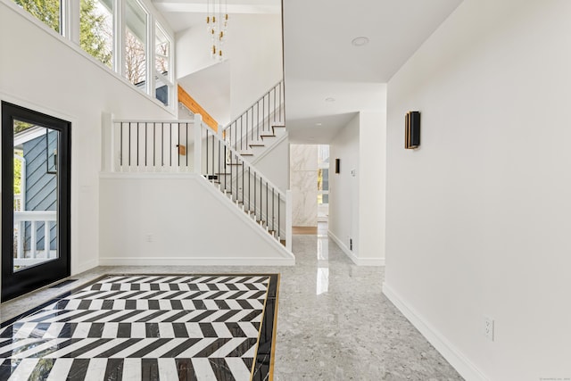 entrance foyer featuring a chandelier, stairway, a high ceiling, and baseboards