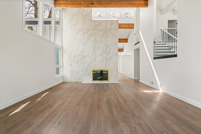 unfurnished living room featuring baseboards, a healthy amount of sunlight, and stairs