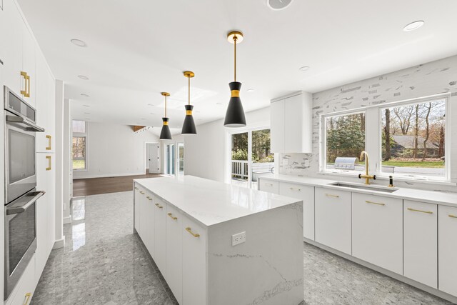 kitchen featuring recessed lighting, double oven, granite finish floor, a sink, and a kitchen island