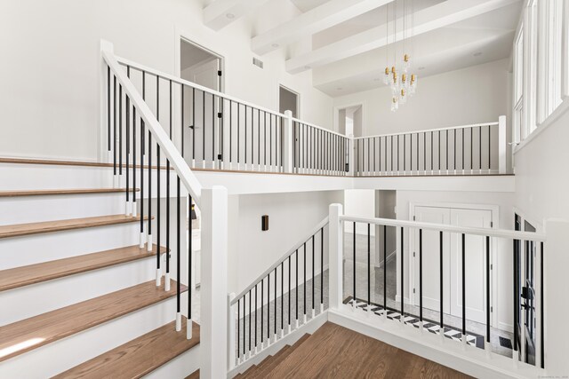 stairs with wood finished floors, visible vents, and a notable chandelier