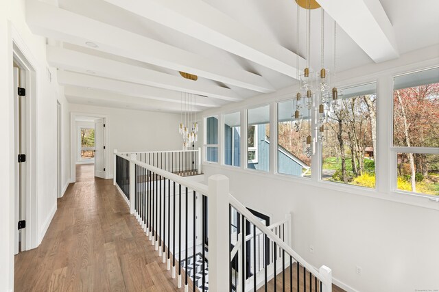 hall featuring an inviting chandelier, wood finished floors, an upstairs landing, beam ceiling, and baseboards