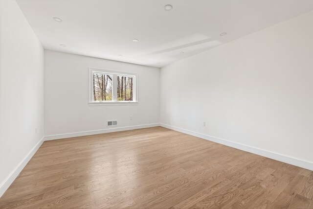 empty room featuring baseboards, light wood finished floors, and visible vents