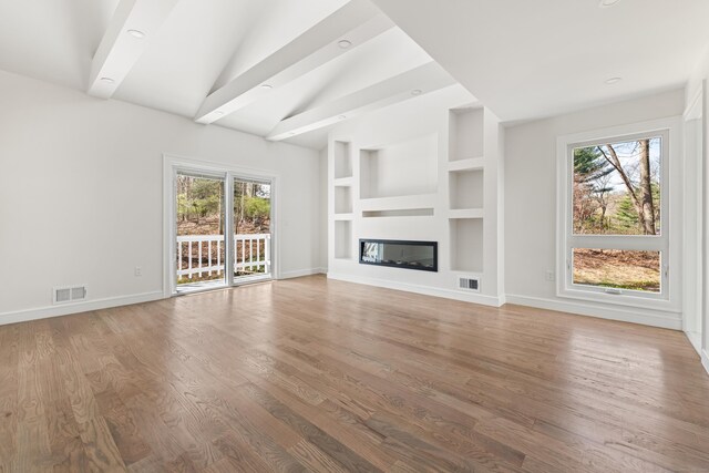 unfurnished living room featuring baseboards, wood finished floors, visible vents, and built in shelves