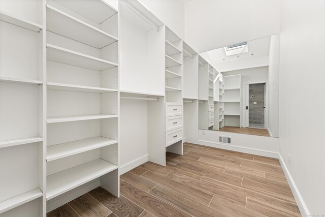 walk in closet with a skylight, wood finished floors, and visible vents