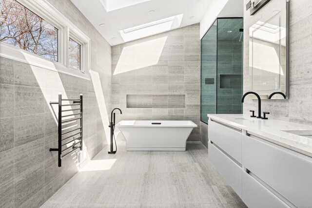 bathroom with radiator heating unit, a soaking tub, a skylight, and tile walls