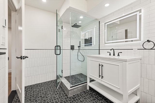 full bath with tile walls, vanity, recessed lighting, and a shower stall