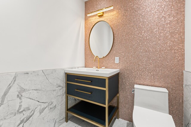 bathroom featuring tile walls, marble finish floor, vanity, and toilet