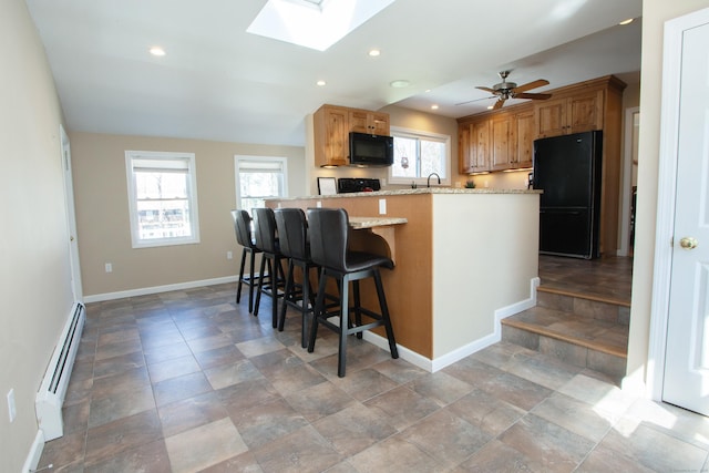 95 Hop Brook Rd, Simsbury, CT 06070 - kitchen featuring black appliances, a skylight, baseboard heating, baseboards, and recessed lighting