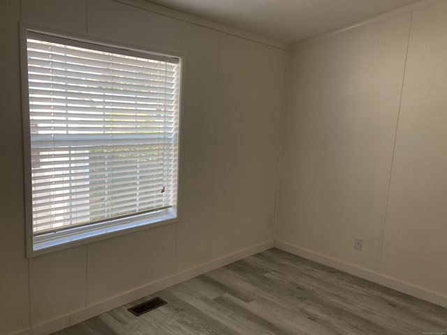 spare room with visible vents, ornamental molding, baseboards, and wood finished floors