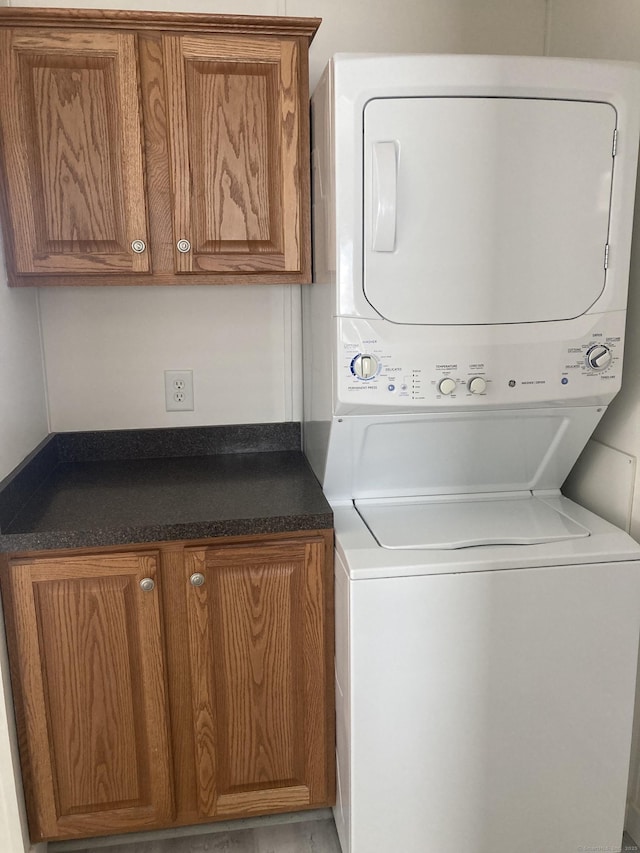 laundry room with cabinet space and stacked washer and clothes dryer