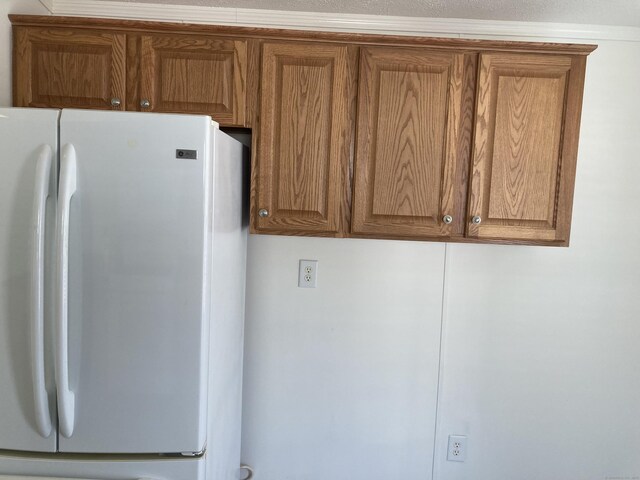 kitchen with freestanding refrigerator and brown cabinetry
