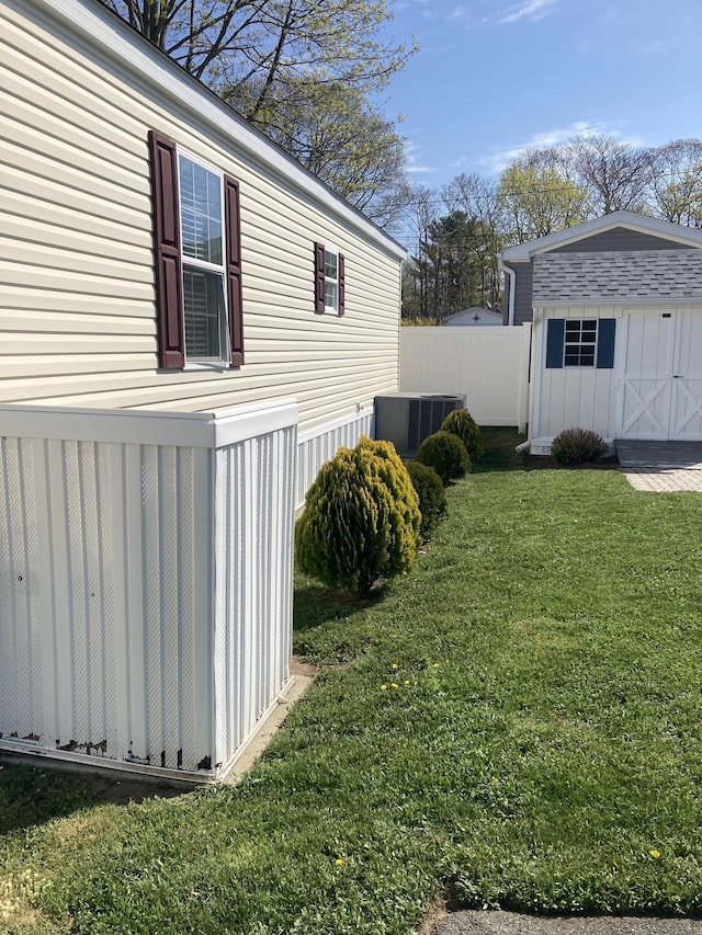 view of yard with central AC, a shed, an outbuilding, and fence