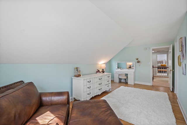 bedroom featuring light wood finished floors, vaulted ceiling, and baseboards