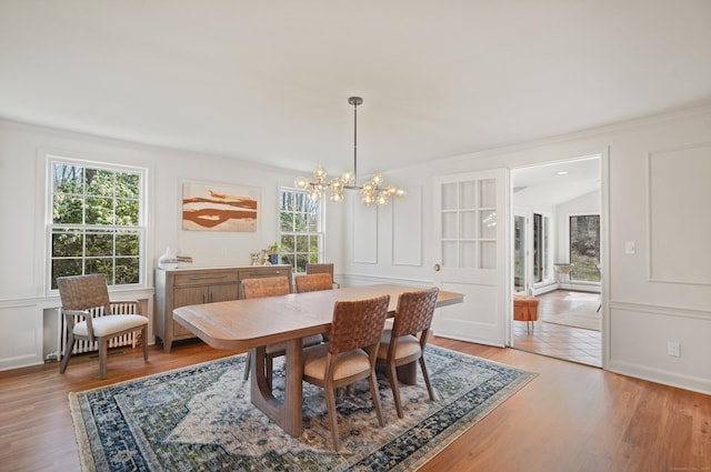 dining room featuring a chandelier, radiator, light wood-style floors, and crown molding