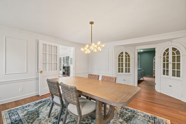 dining room featuring wood finished floors, a chandelier, and ornamental molding