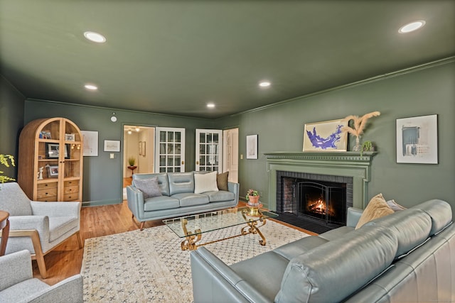 living area featuring a fireplace, wood finished floors, recessed lighting, and ornamental molding
