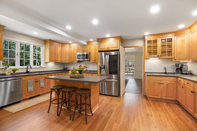 kitchen with dark countertops, light wood-style flooring, appliances with stainless steel finishes, and a sink