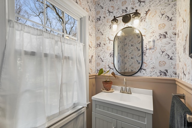 bathroom with vanity, a wainscoted wall, and wallpapered walls