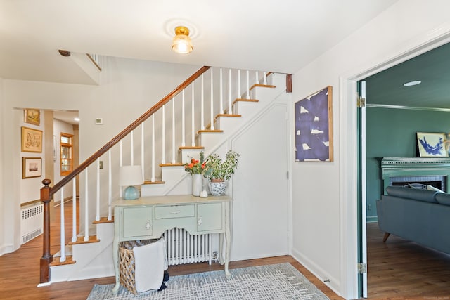 staircase featuring radiator, baseboards, and wood finished floors